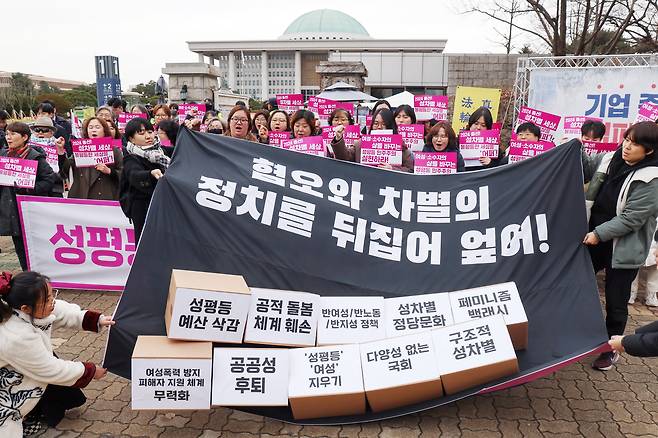 2024 총선을 앞둔 지난해 연말 출범한 여성 주권자 행동 '어퍼'의 출범식. 여의도 국회 앞에서 성차별을 부추기는 사회적 문제들이 적힌 상자를 뒤엎는 퍼포먼스를 하고 있다. /뉴스1