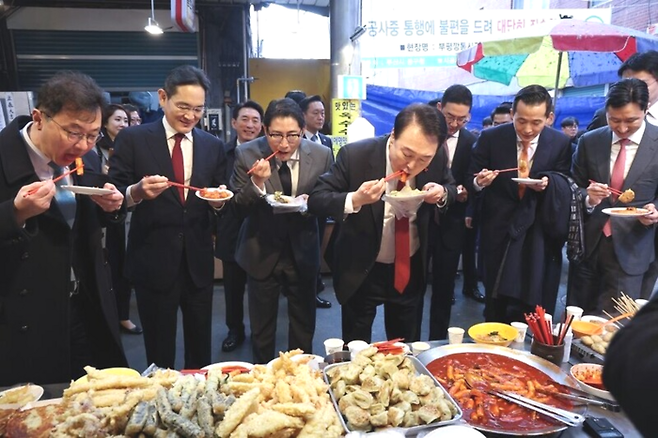 윤석열 대통령이 지난해 12월 6일 부산 중구 깡통시장에서 재계 총수들과 함께 떡볶이 튀김 빈대떡을 맛보고 있다. [사진출처 = 연합뉴스]