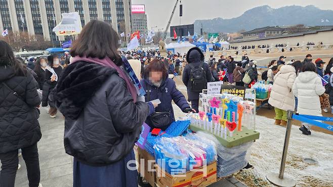 21일 오후 서울 종로구 광화문 집회 장소 인근에서 한 노점상이 응원봉과 방석 등을 판매하는 모습. (사진=박동현 기자)