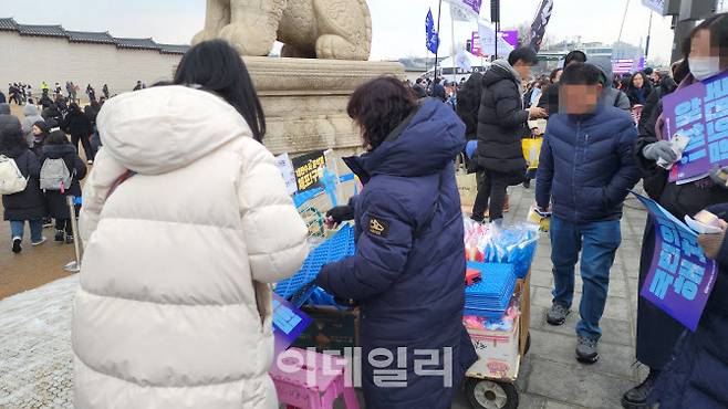 21일 오후 서울 종로구 광화문 집회 장소 인근에서 한 노점상이 응원봉과 방석 등을 판매하는 모습. (사진=박동현 기자)