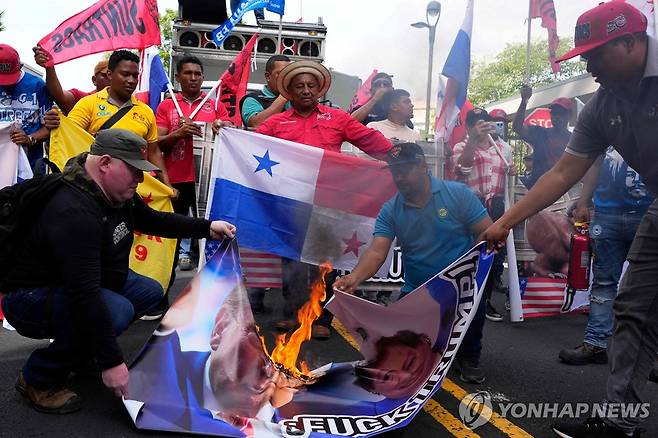 트럼프 얼굴 현수막에 불 지르는 파나마 주민들 (파나마시티 AFP=연합뉴스) 24일(현지시간) 파나마 수도 파나마시티에 있는 미국 대사관 앞에서 주민들이 파나마 운하 통제권 반환 요구 가능성을 언급한 도널드 트럼프 미 대통령 당선인에 대해 반대 시위를 하며 트럼프 얼굴 사진을 인쇄한 현수막에 불을 지르고 있다. 2024.12.25