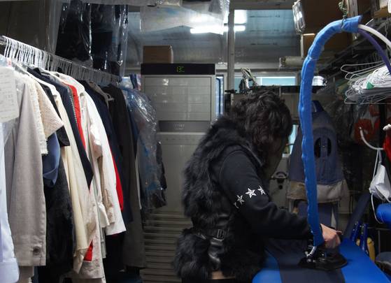 Dry cleaner owner Kim Seon-mi has been in the hand laundry business for more than 30 years. She opened her current shop in Suwon, Gyeonggi, where she is pictured in the photo ironing suit pants, with her husband in 2002. [KIM JU-YEON]