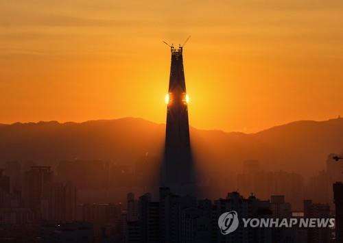 새로운 해, 뜨겁게 타오른다 (서울=연합뉴스) 서명곤 기자 = 사진은 시공 중인 잠실 롯데월드타워 뒤로 해가 떠오르는 모습. 2015.12.30