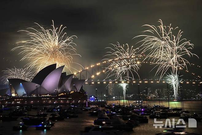 [시드니=AP/뉴시스] 31일(현지시각) 호주 시드니에서 새해 전야제 행사가 열려 오페라하우스와 하버 브리지 상공에 화려한 불꽃이 터지고 있다. 2024.12.31.