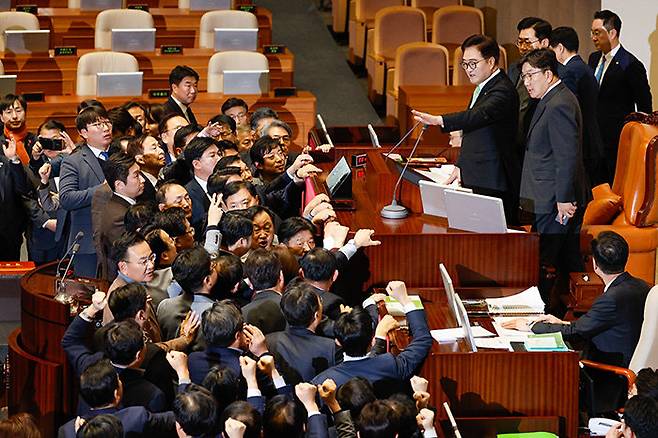 12월 27일 국회 본회의에서 우원식 국회의장이 한덕수 대통령 권한대행 탄핵안 표결 의결 정족수를 ‘재적 과반’으로 선언하자 국민의힘 의원들이 의장석으로 몰려가 항의하고 있다. [뉴스1]