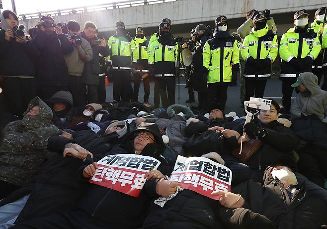 고위공직자범죄수사처가 내란 수괴(우두머리)·직권남용 혐의를 받는 윤석열 대통령의 체포영장을 유효기간인 6일 이전에 집행하겠다고 밝힌 가운데 1월2일 서울 용산구 한남동 대통령 관저 정문 앞 도로에 지지자들이 손팻말을 들고 누워있다. ⓒ연합뉴스