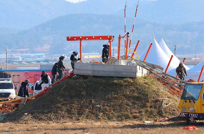 3일 오전 전남 무안군 무안국제공항 제주항공 여객기 참사 현장에서 항공철도사고조사위원회 및 국과수 관계자 등이 엔진을 살피기 위해 방위각시설(로컬라이저)을 오르고 있다. [연합]