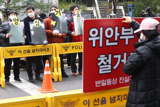 2021년 12월15일 서울 종로구 옛 주한일본대사관 앞에서 열린 일본군 위안부 피해자 문제 해결을 위한 정기 수요시위에서 참가자들이 집회를 방해하는 극우단체를 향해 ‘양심거울\'을 들어 보이고 있다. 연합뉴스