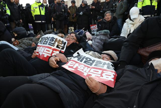 고위공직자범죄수사처가 내란 수괴(우두머리) 등 혐의를 받는 윤석열 대통령에 대한 체포영장을 집행하겠다고 예고한 가운데 지난 2일 서울 한남동 대통령 관저 정문 앞에서 윤 대통령 지지층이 '계엄합법 탄핵무효'라고 쓰인 피켓을 들고 길에 누워 있다. 연합뉴스