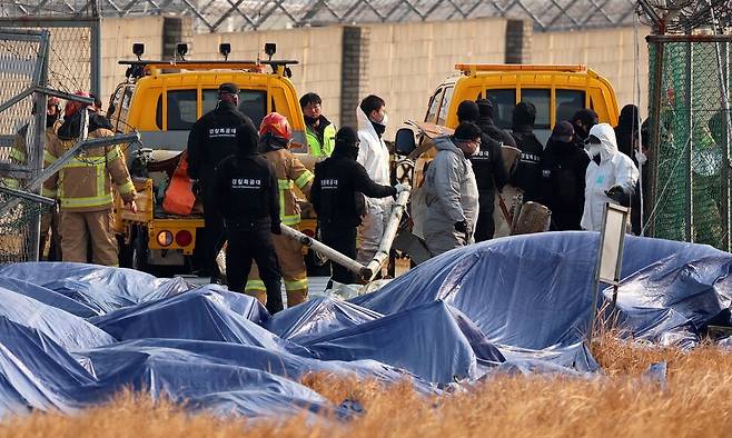 제주항공 여객기 참사 9일째인 6일 오전 전남 무안공항에서 경찰특공대원과 소방대원들이 울타리 밖에 있던 기체 잔해를 옮기고 있다. 연합뉴스