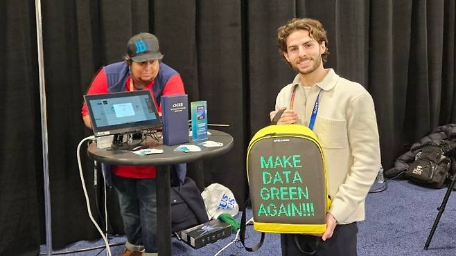 5일 미국 라스베이거스 만델레이 호텔에서 열린 CES 2025 ‘언베일드(Unveiled)’ 행사에서 프랑스 스타트업 ‘데이터 그린’ 관계자가 백팩을 들어 보이고 있다. 중형 데이터 센터를 가방 크기까지 줄일 수 있다는 점을 강조하기 위한 퍼포먼스다. 이 회사 관계자는 “기존 데이터 센터보다 전력 사용량은 75%, 탄소 배출량은 82% 줄였다”고 했다. /라스베이거스=박지민 기자