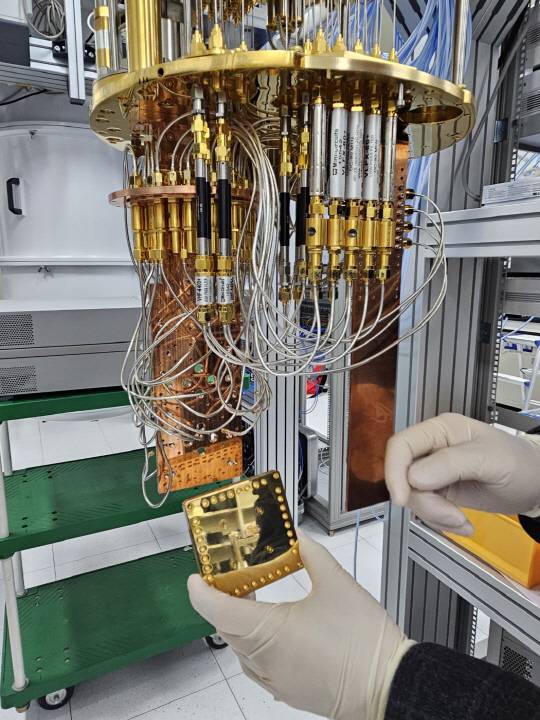 표준연 연구진이 20큐비트 양자컴퓨터 성능 테스트를 위해 양자 프로세서를 양자컴퓨터에 탑재하고 있다.