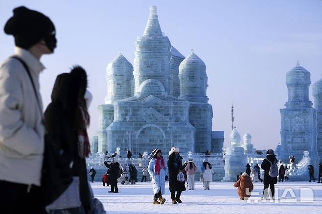 [하얼빈=AP/뉴시스] 6일 중국 헤이룽장성 하얼빈에서 열린 제41회 하얼빈 빙설제에서 관광객들이 얼음 조각을 관람하고 있다. 2025.01.10.