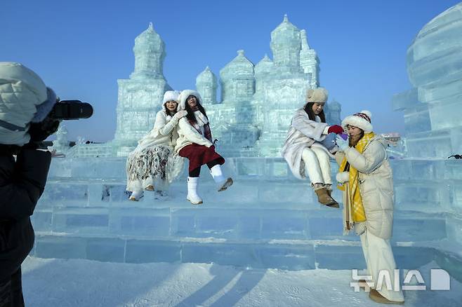 [하얼빈=AP/뉴시스] 6일 중국 헤이룽장성 하얼빈에서 열린 제41회 하얼빈 빙설제에서 관광객들이 기념촬영을 하고 있다. 2025.01.10.