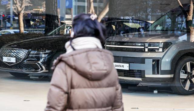 정부가 소비 활력을 제고를 위해 자동차 구입 시 상반기 한시적으로 개별소비세율을 5%에서 3.5%로 30% 인하한다. 2일 오후 서울의 한 자동차 영업점 앞을 한 시민이 지나고 있다. 이와 함께 3% 적용 예정이던 올해 자동차세 연납 할인율도 작년과 같은 5%로 유지된다. 뉴스1