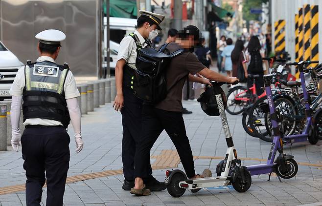 An e-scooter rider is stopped by police for not wearing a helmet near Seongsu Station in Seongdong-gu, Seoul. (Getty Images Bank)