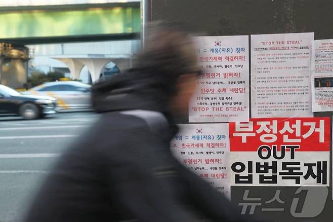 윤석열 대통령이 체포된 15일 오후, 자전거를 탄 시민이 한남대로 육교 기둥에 붙은 윤석열 대통령 지지자들의 전단을 바라보고 있다.2025.01.15/뉴스1 ⓒ 뉴스1 김민재 기자