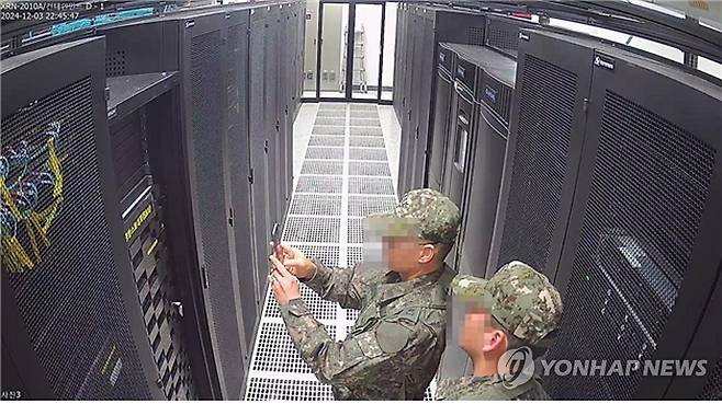 CCTV에 기록된 계엄군의 선관위 시스템서버 촬영 모습 (서울=연합뉴스) 국회 행정안전위원회는 지난해 12월 3일 계엄령 선포 당시 선거관리위원회에 투입된 계엄군이 선관위 시스템 서버를 촬영하는 장면이 담긴 CCTV를 12월 6일 공개했다. 2024.12.6 [행정안전위원회 제공. 재판매 및 DB 금지] utzza@yna.co.kr