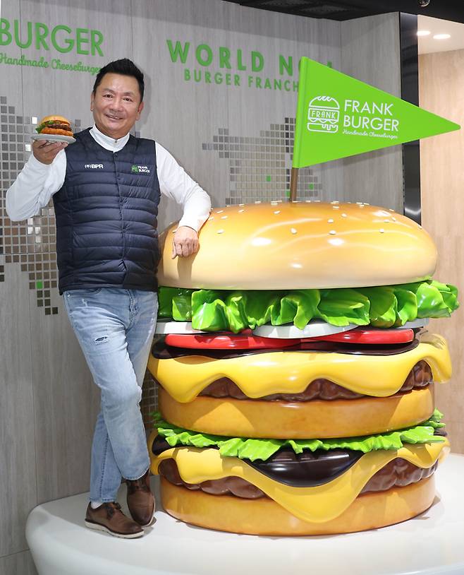 심우창 프랭크에프앤비 회장이 인천 서구 프랭크버거 본사에서 버거를 들고 포즈를 취하고 있다.  <이충우 기자>