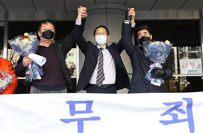 ‘낙동강변 살인사건’ 범인으로 지목돼 21년간 옥살이를 한 장동익씨와 최인철씨가 2021년 12월 4일 부산 연제구 부산고등법원에서 열린 재심 선고 공판을 앞두고 박준영 변호사(가운데)와 손을 들어보이고 있다. 두 사람은 무죄 판결을 받았다. /뉴스1