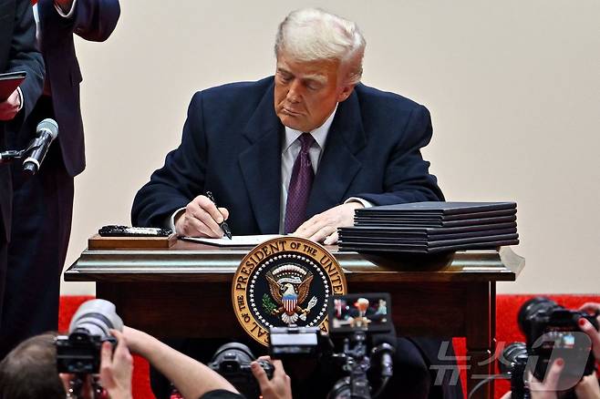 도널드 트럼프 미국 대통령이 20일(현지시간) 워싱턴 '캐피털원 아레나'에서 열린 제47대 대통령 취임 축하 퍼레이드에 참석해 지지자들 앞에서 파리 기후변화 협정 재탈퇴를 비롯한 행정명령에 서명을 하고 있다. 2025.01.21 ⓒ AFP=뉴스1 ⓒ News1 우동명 기자