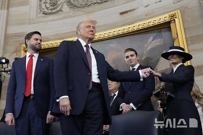 [워싱턴=AP/뉴시스] 도널드 트럼프 미국 대통령 당선인이 20일(현지 시간) 본인의 제47대 대통령 취임식이 열리는 미 연방의회 의사당 로툰다 홀에 입장해 앞서 입장한 부인 멜라니아 여사의 손을 잡고 있다. 2025.01.21.