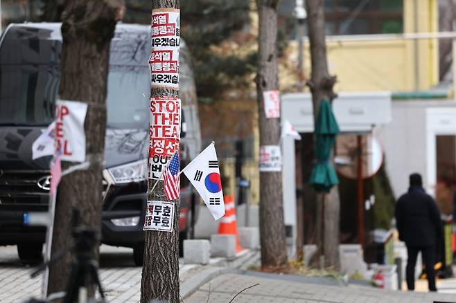 윤석열 대통령이 내란 수괴 혐의로 공수처에 체포된 다음 날인 16일 서울 용산구 한남동 대통령 관저 인근 나무에 체포 반대 집회에 쓰인 팻말과 태극기가 붙어있다. /사진=연합뉴스