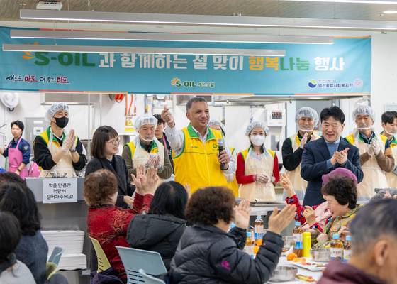 S-Oil CEO Anwar A. AL-Hejazi, center, poses with the Korean finger heart at an event sharing tteokguk , or rice soup that is traditionally eaten in Korea during the Lunar New Year, for those in need at a social welfare center in Mapo District, western Seoul, on Jan. 22. [S-OIL]