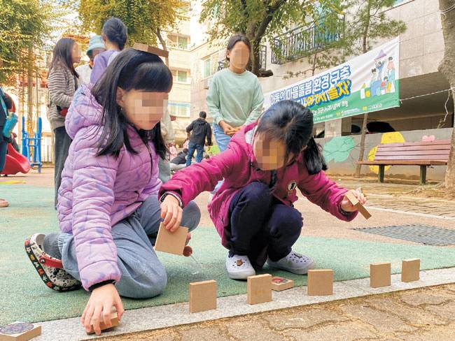 경기 안산시 단원구 선부2동 땟골 공원에서 진행된 선부종합사회복지관의 ‘안전한 놀이터, 여기서 놀자’ 사업에 참여한 어린이들이 지난해 10월 나무 놀잇감을 가지고 전통놀이를 하고 있다.  초록우산 제공