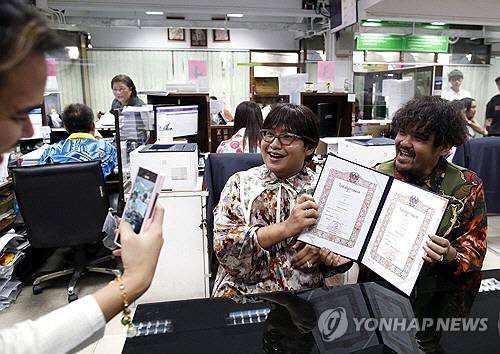 태국에서 동성 결혼이 합법화된 첫 날인 지난 23일(현지시간) 태국 방콕 방락 구청에서 남성 동성 부부가 혼인신고를 한 뒤 혼인증명서를 들어 보여주고 있다.   [EPA 연합뉴스 자료사진]