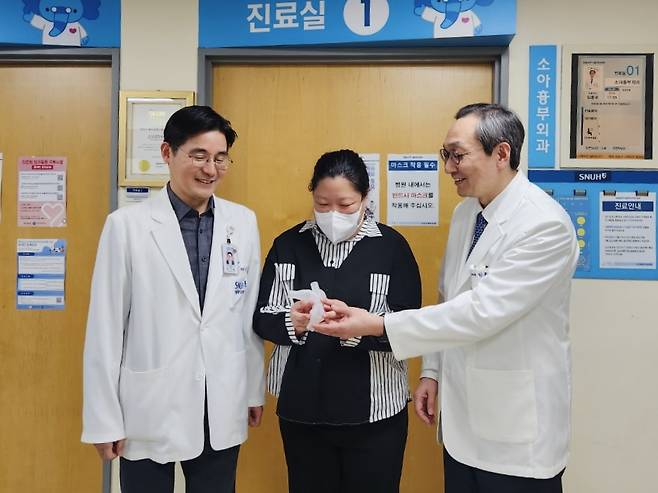 Profs. Lim Hong-gook, right, and Kim Gi-beom, left, smile with a patient named Kim Ji-eun, who received pulmonary valve implantation surgery at Seoul National University Hospital in Seoul. The patient holds a 3D-printed replica of her heart. [SEOUL NATIONAL UNIVERSITY HOSPITAL]