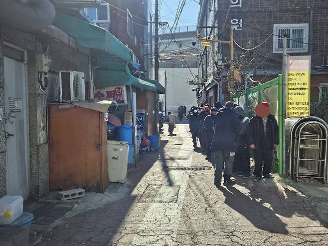 [서울=뉴시스]이명동 기자 = 4일 오전 서울 영등포구 영등포역 6번 출구 앞 급식소인 토마스의 집 이용을 원하는 방문자가 개장 전 옆 골목에서 기다리고 있다. 전국 대부분 지역에 한파특보가 이날 따뜻한 국물과 김이 피어오르는 쌀밥을 찾아온 쪽방촌 주민 등 60여 명은 토마스의 집 운영 전부터 줄지어 서서 급식소 개장을 기다렸다. 2025.02.04. ddingdong@newsis.com *재판매 및 DB 금지