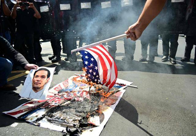 2일 파나마 수도 파나마시티에서 도널드 트럼프 미국 대통령의 '파나마운하 운영권 환수' 주장에 반발하는 시위대가 트럼프 대통령·마코 루비오 미 국무장관 사진과 함께 성조기를 불태우고 있다. 파나마시티=AFP 연합뉴스