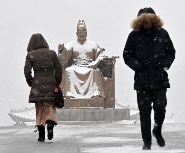 한파와 함께 전국 곳곳에 눈이 내린 7일 서울 종로구 광화문광장에서 시민들이 두꺼운 외투와 털모자를 쓴 채 출근하고 있다. 홍인기 기자