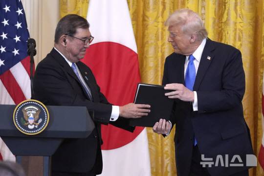 도널드 트럼프 미국 대통령이 7일(현지 시간) 백악관에서 이시바 총리와 회담한 후 공동기자회견에서 함께 찍은 사진을 선물하고 있다. 뉴시스