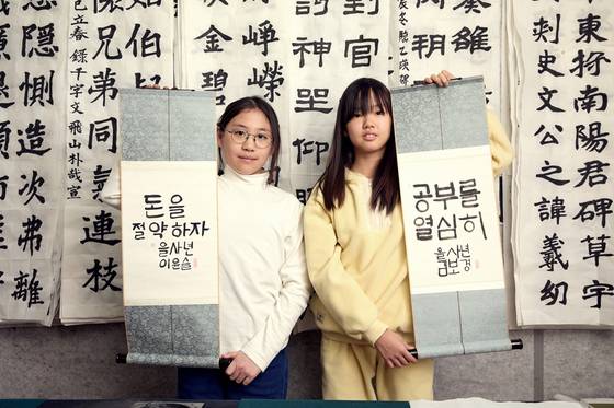 이윤슬(왼쪽)·김보경 학생기자가 한글서예의 기초를 배운 뒤, 판본체로 새해 결심을 족자에 썼다.