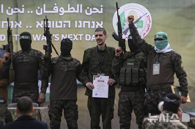 [가자지구=AP/뉴시스] 팔레스타인 무장 정파 하마스는 오는 15일로 예정된 이스라엘 인질 6차 석방을 연기한다고 10일(현지 시간) 밝혔다. 하마스는 지난 8일 5차 인질 석방으로 이스라엘 인질 3명을 석방했다. 사진은 하마스 무장대원이 인질 석방에 앞서 이스라엘 인질 오르 레비(34·가운데)와 함께 사진을 찍는 모습. 2025.02.11.