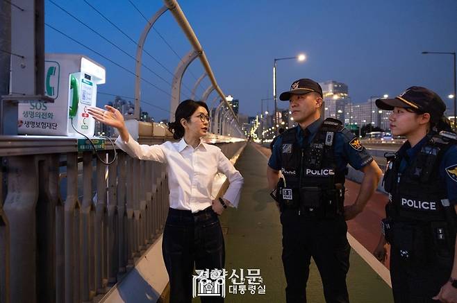김건희 여사가 지난해 9월 10일 서울 마포대교에서 마포경찰서 근무자와 함께 ‘생명의 전화’를 살펴보며 대화하고 있다. 대통령실 제공