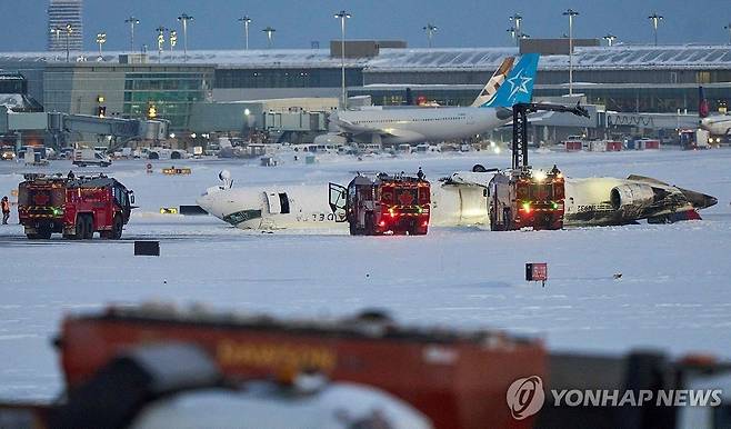 토론토 공항서 사고로 뒤집힌 여객기  (토론토 AFP=연합뉴스) 17일(현지시간) 캐나다 토론토 피어슨 국제공항에서 직원들이 여객기 사고 현장을 수습하고 있다. 2025.2.18