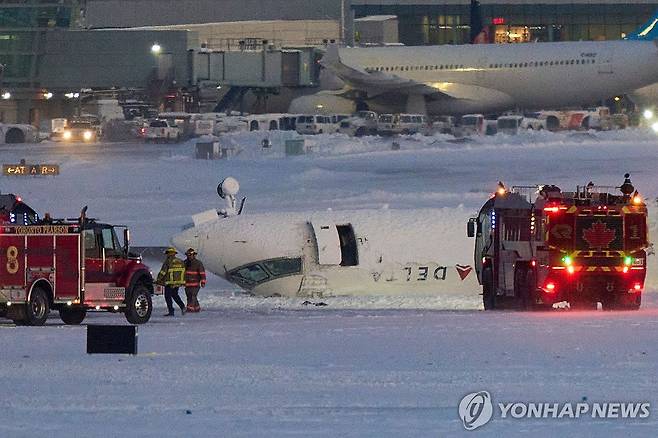 토론토 공항서 사고로 뒤집힌 여객기  (토론토 AFP=연합뉴스) 17일(현지시간) 캐나다 토론토 피어슨 국제공항에서 직원들이 여객기 사고 현장을 수습하고 있다. 2025.2.18