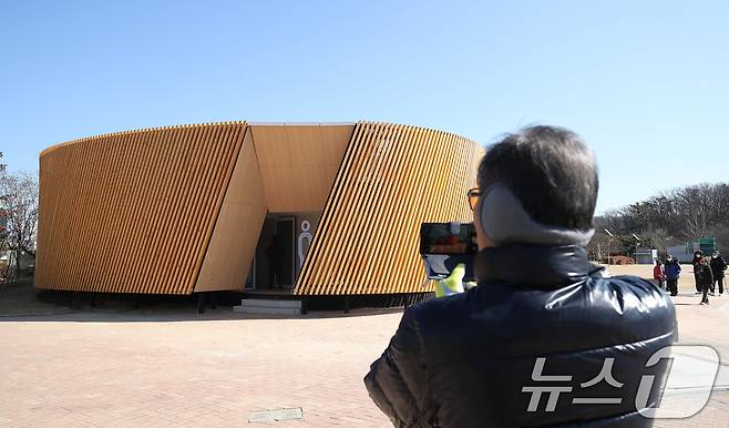 대구 수성구 수성못 상화동산 공중화장실이 최근 리모델링 공사를 마치고 개방됐다. 스페인 건축가의 설계를 바탕으로 예술적 요소를 강조한 이 화장실 리모델링 공사에 수성구가 예산 9억 원을 투입한 사실이 알려지며 논란이 일고 있다. 20일 수성못을 찾은 한 시민이 공중화장실 외관을 휴대전화로 촬영하고 있다. 2025.2.20/뉴스1 ⓒ News1 공정식 기자