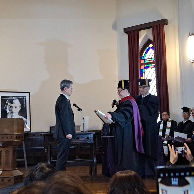 윤동주의 장조카이자 유족 대표로 행사에 참석한 윤인석(왼쪽) 성균관대 명예교수가 16일 교토 도시샤대학에서 열린 윤동주 명예문화박사 증정식에서 학위 증서를 받고 있다. 도시샤대학 한국교우회 제공