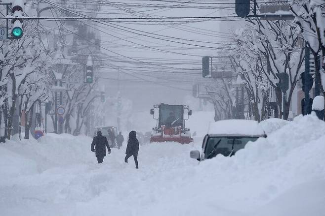 지난 4일 일본 홋카이도에 폭설이 쏟아지자 중장비가 도로를 치우고 있다. AFP 연합뉴스