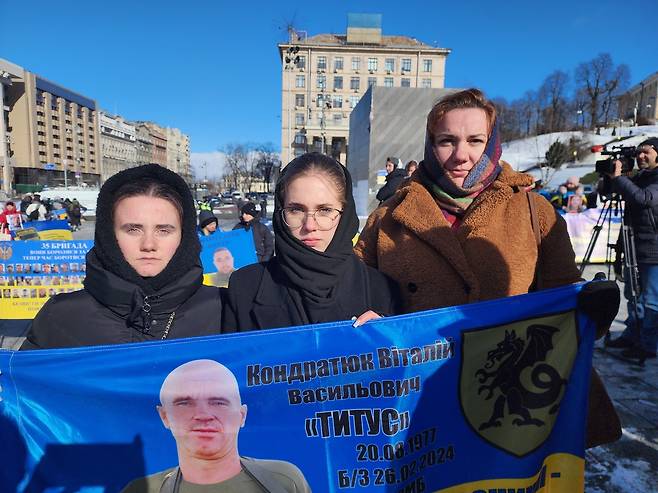 "아버지, 살아서 돌아오세요" (키이우=연합뉴스) 신창용 특파원 = 20일(현지시간) 우크라이나 수도 키이우의 독립광장에서 리우바 씨(오른쪽)가 이복동생들과 함께 양아버지의 사진이 담긴 펼침막을 들고 있다. 2025.02.20 changyong@yna.co.kr