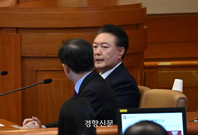 윤석열 대통령이 지난 20일 오후 서울 종로구 헌법재판소에서 열린 탄핵심판 10차 변론에 출석해 윤갑근 변호사와 이야기를 나누고 있다. 사진공동취재단