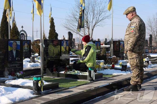 러시아의 우크라이나 침공 3주년을 맞은 24일(현지시간) 우크라이나 부차의 묘지에서 시민들이 전사한 아들을 추모하고 있다. ⓒ 로이터=뉴스1
