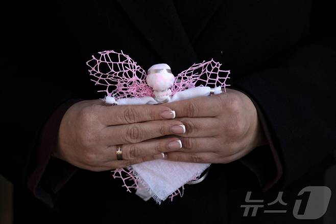 러시아의 우크라이나 침공 3주년을 맞이한 24일(현지시간) 우크라이나 키이우 외곽 이르핀에 위치한 전쟁 초기에 파괴된 로마니브스카 다리에서 열린 기념 행사에서 한 여성이 천사 인형을 들고 있다. ⓒ 로이터=뉴스1