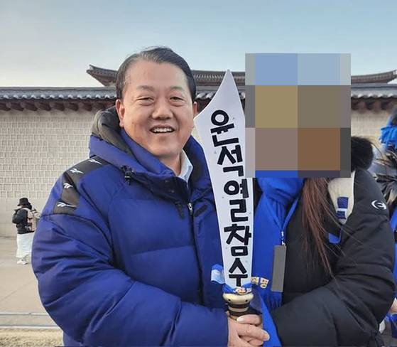 김병주 더불어민주당 의원이 지난 22일 윤석열 파면 촉구 범국민대회에 참석해 '윤석열 참수'라고 적힌 모형 칼을 들고 지지자와 함께 사진을 찍었다. 사진 박민영 국민의힘 대변인 페이스북 캡쳐