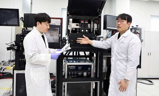 우규희 책임연구원(오른쪽)이 롤투롤 호환 플래시 공정 장비에 대해 설명하고 있다.[한국기계연구원 제공]