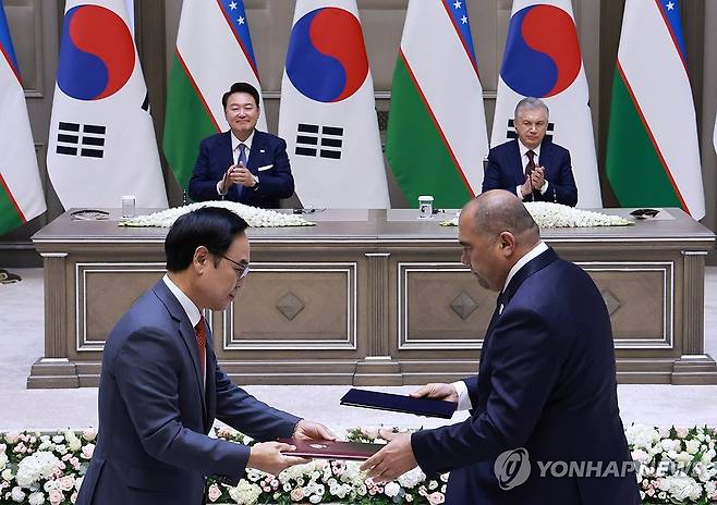 현대로템, 우즈베키스탄 철도공사 고속철 6편성 공급계약 (타슈켄트[우즈베키스탄]=연합뉴스) 홍해인 기자 = 이용배 현대로템 사장과 주파르 나르줄라예프 우즈베키스탄철도공사 사장이 14일(현지시간) 우즈베키스탄 타슈켄트 대통령궁에서 열린 한·우즈베키스탄 협정 및 양해각서(MOU) 서명식에서 '우즈베키스탄 철도공사 고속철 6편성 공급계약'에 서명 뒤 문서를 교환하고 있다. 이날 협정 및 MOU 서명식에는 윤석열 대통령과 샤브카트 미르지요예프 우즈베키스탄 대통령이 임석했다. 2024.6.14 hihong@yna.co.kr